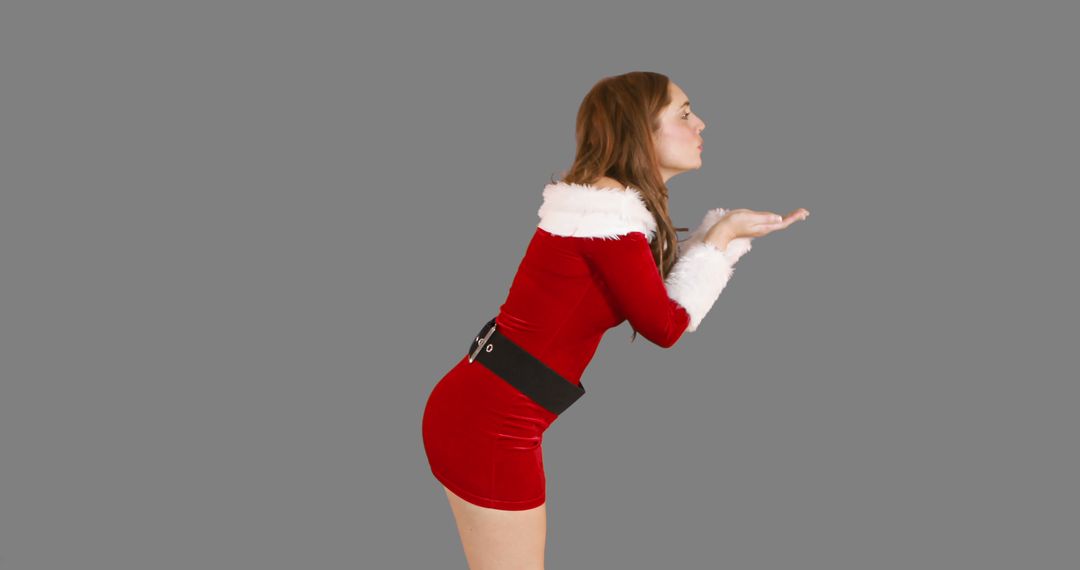 Woman in Santa Outfit Blowing a Kiss on Gray Background - Free Images, Stock Photos and Pictures on Pikwizard.com