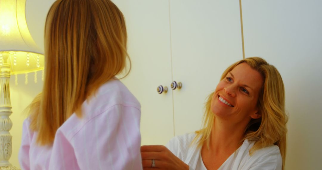 Mother Smiling While Dressing Daughter in Bedroom - Free Images, Stock Photos and Pictures on Pikwizard.com