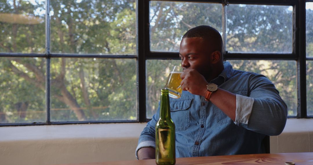 Man Enjoys Refreshing Beer by Sunlit Window
