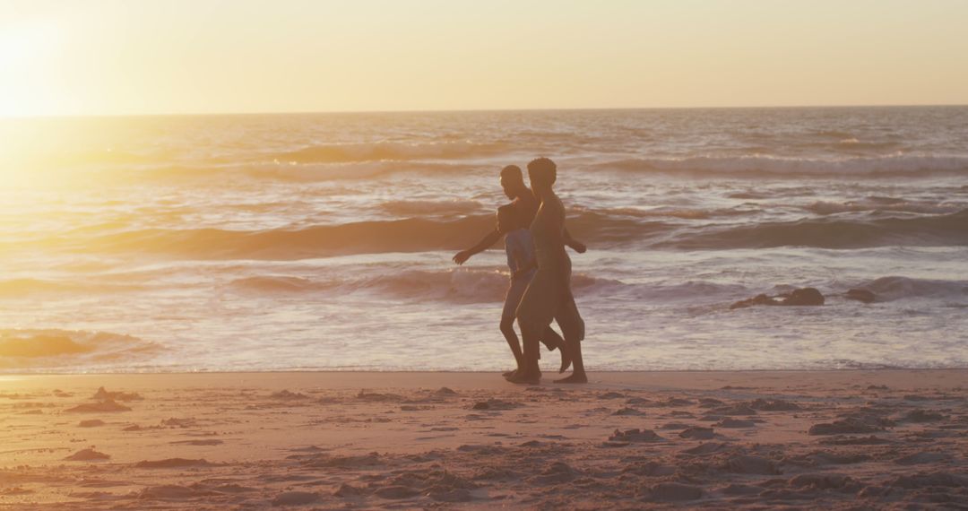 Couple Walking on Sunny Beach at Sunset - Free Images, Stock Photos and Pictures on Pikwizard.com