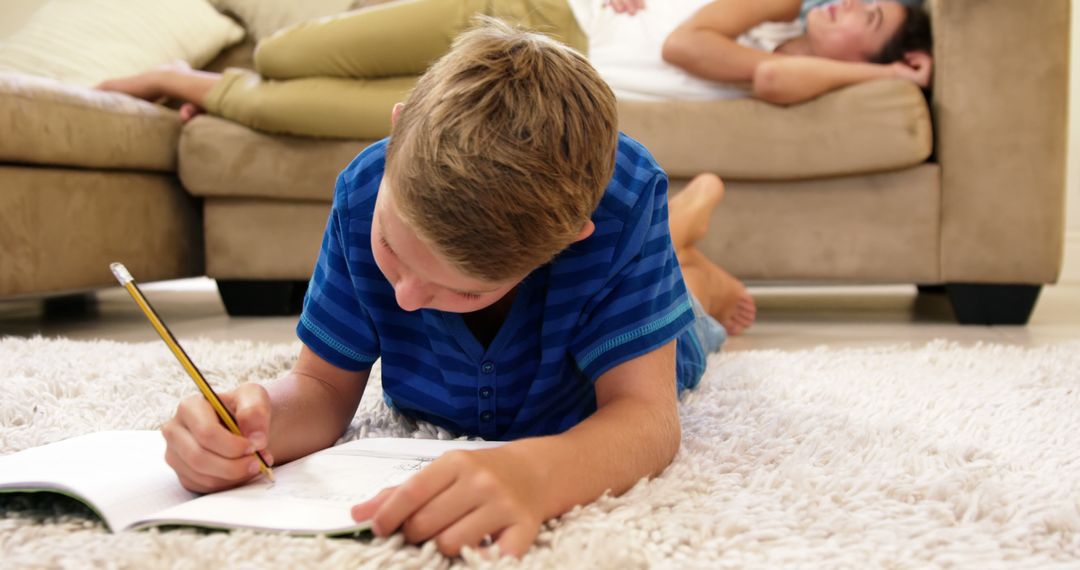 Young Boy Drawing on Floor While Mother Rests on Couch - Free Images, Stock Photos and Pictures on Pikwizard.com