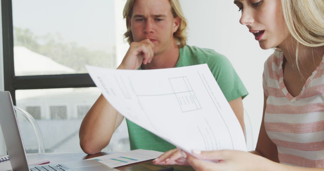 Couple Reviewing Documents and Using Laptop at Home