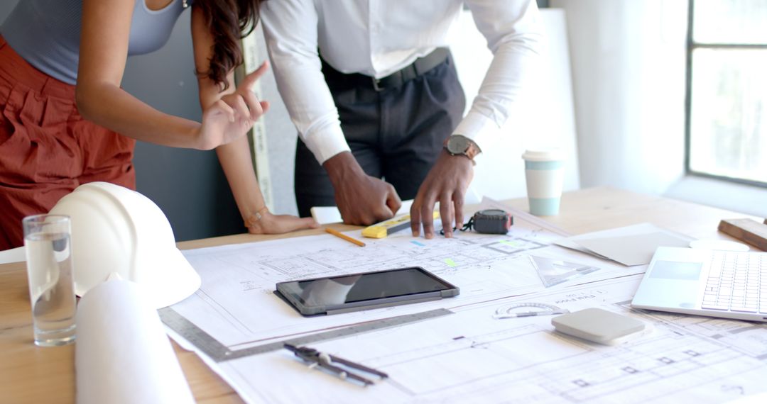 Collaborative Architectural Planning Meeting with Tablet and Blueprints