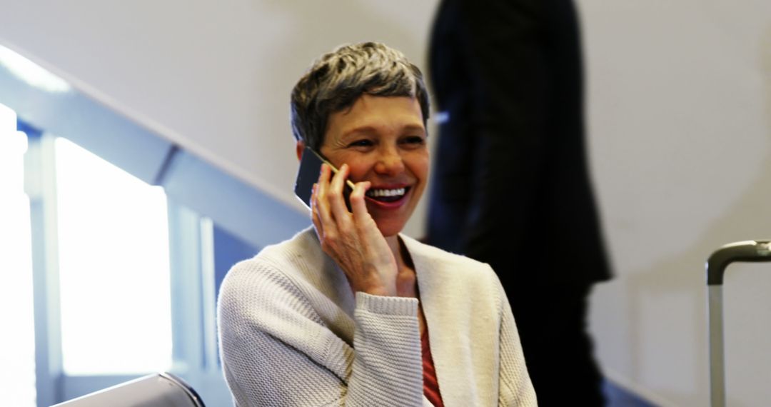 Woman Smiling While Speaking on Mobile Phone in Airport Terminal