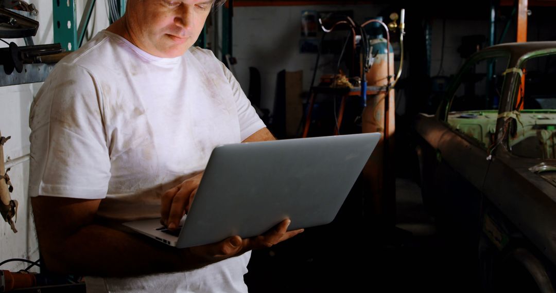 Mechanic Using Laptop While Working in Garage - Free Images, Stock Photos and Pictures on Pikwizard.com