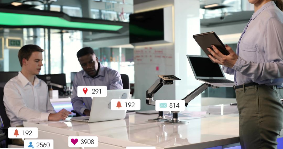 Business team collaborating at office desk with laptops, tablet and notification icons