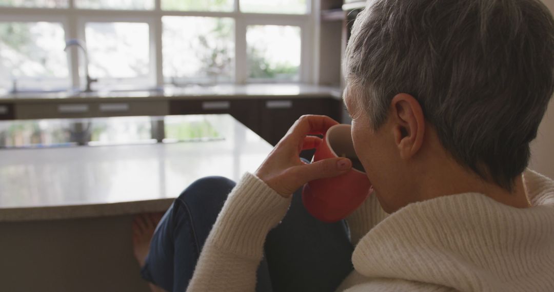 Woman Relaxing in Modern Kitchen with Cup of Coffee - Free Images, Stock Photos and Pictures on Pikwizard.com