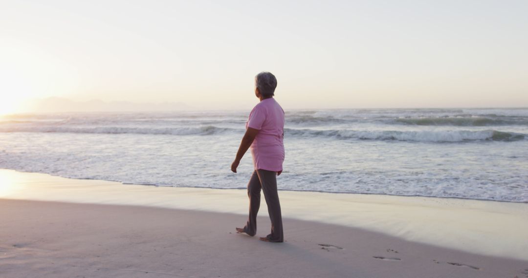 Senior Woman Walking on Beach at Sunset - Free Images, Stock Photos and Pictures on Pikwizard.com