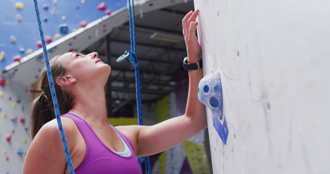 Nervous caucasian woman preparing to climb a wall at indoor climbing wall - Free Images, Stock Photos and Pictures on Pikwizard.com