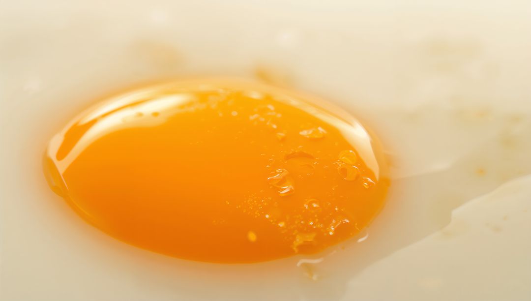 Glistening Fried Egg Yolk Closeup Macro with Salt Droplets and Glossy Orange Texture