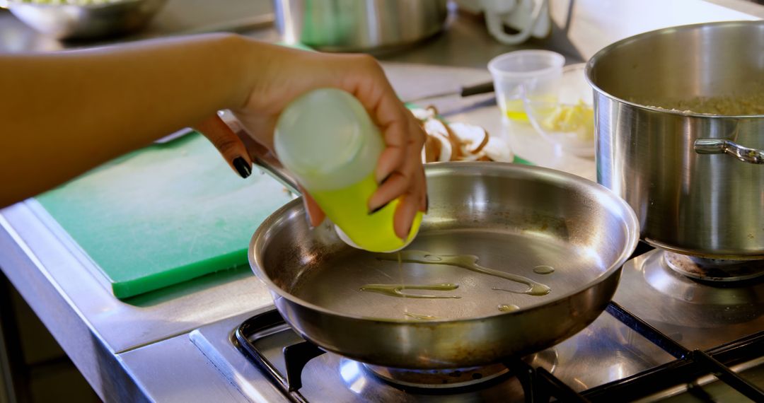 Person pouring oil into frying pan in kitchen - Free Images, Stock Photos and Pictures on Pikwizard.com