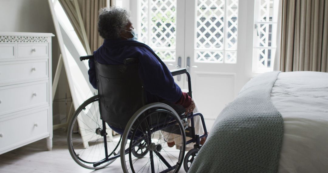 Elderly Woman Looking Out the Window from Wheelchair in Cozy Bedroom - Free Images, Stock Photos and Pictures on Pikwizard.com