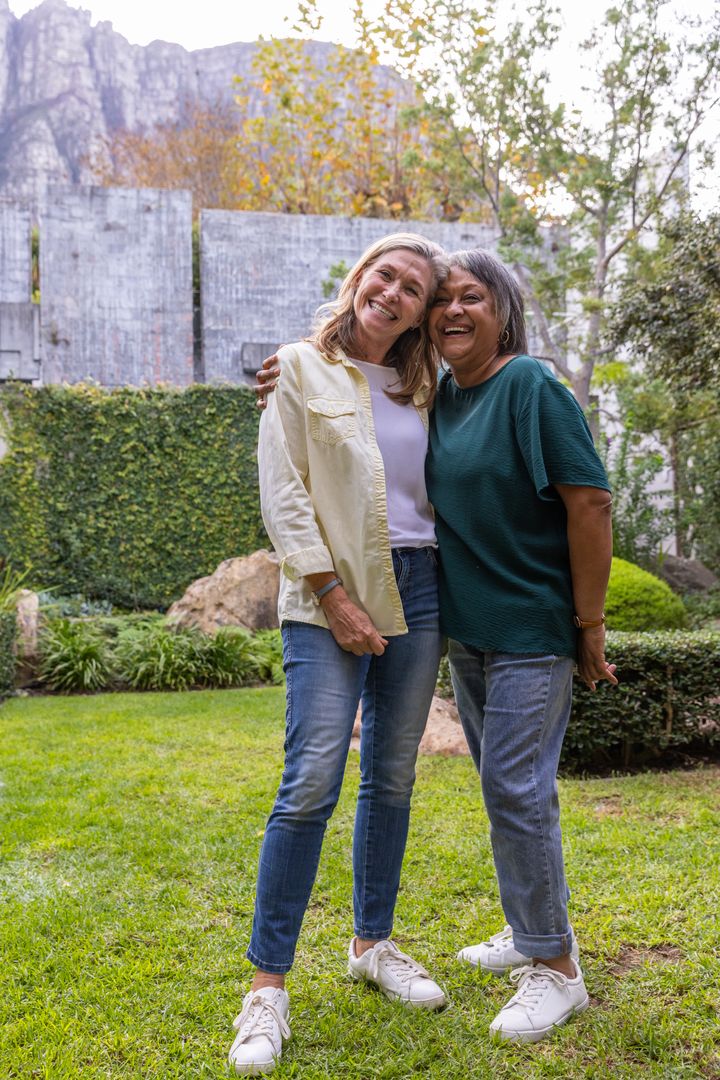 Happy Friends Hugging Outdoors on Grassy Lawn