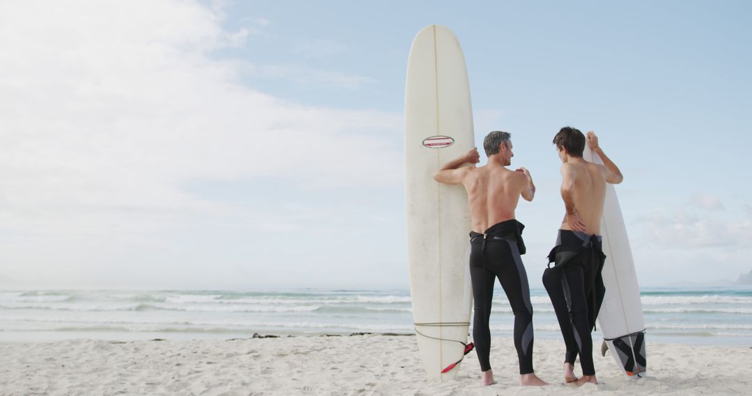 Two Surfers in Black Wetsuits with Surfboards on Beach - Free Images, Stock Photos and Pictures on Pikwizard.com