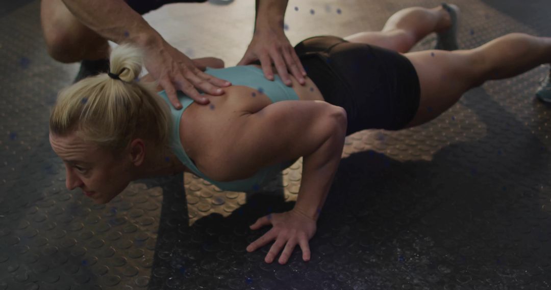 Female Athlete Performing Push-Up with Trainer Support in Gym