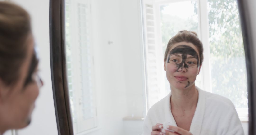 Woman Applying Black Clay Face Mask in Modern Bathroom - Free Images, Stock Photos and Pictures on Pikwizard.com