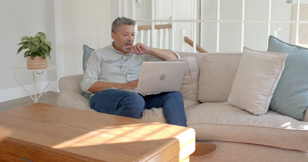 Senior Man Relaxing with Laptop on Couch Enjoying Leisure Time at Home