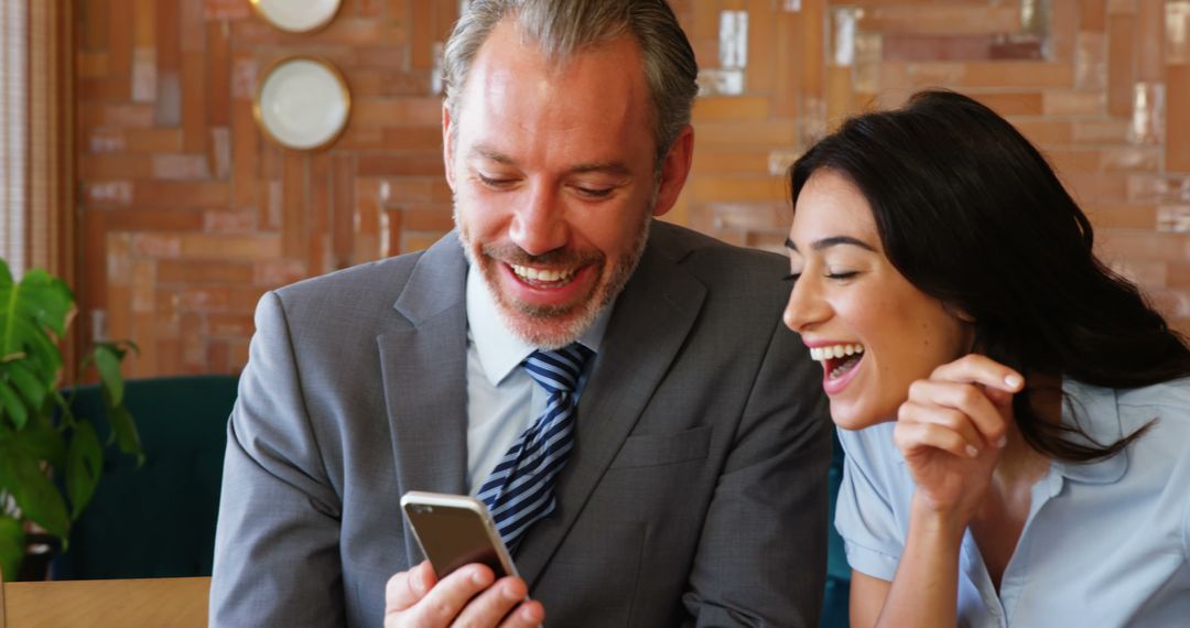 Colleagues Laughing Together While Sharing Phone Content