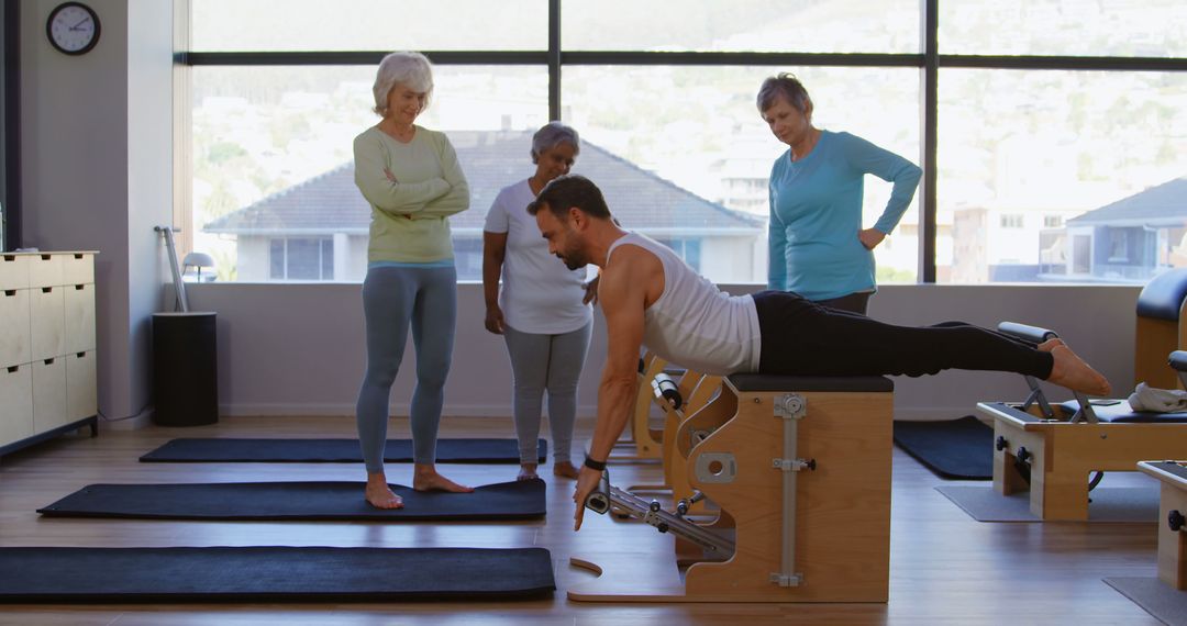 Instructor Demonstrating Exercise to Group in Pilates Studio - Free Images, Stock Photos and Pictures on Pikwizard.com