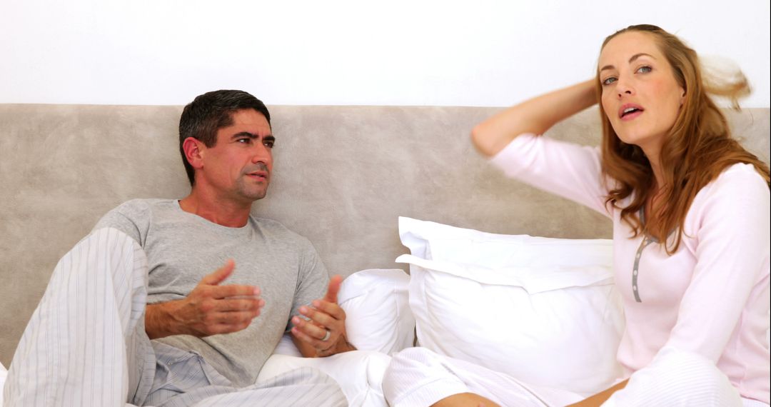 Couple Arguing in Bedroom while Sitting on Bed