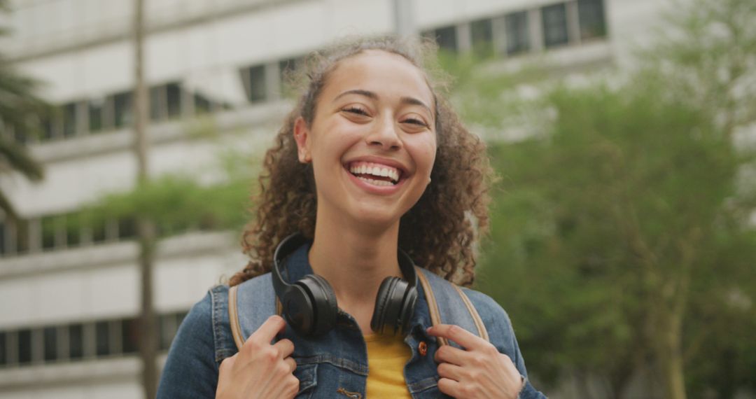 Portrait of happy biracial woman in city, wearing headphones and smiling - Free Images, Stock Photos and Pictures on Pikwizard.com