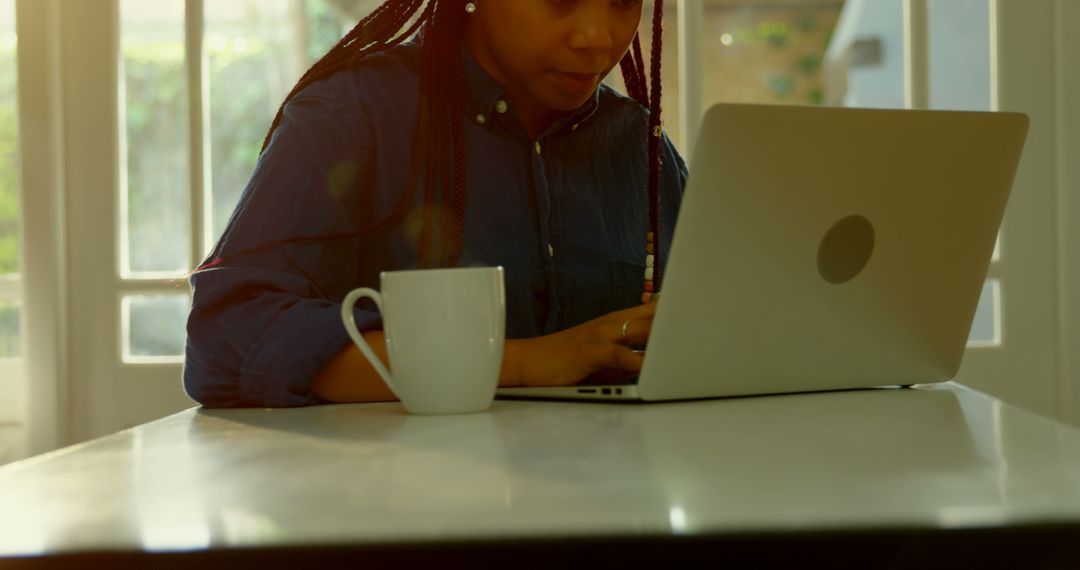 Woman working on laptop in cozy home office with coffee mug on table - Free Images, Stock Photos and Pictures on Pikwizard.com