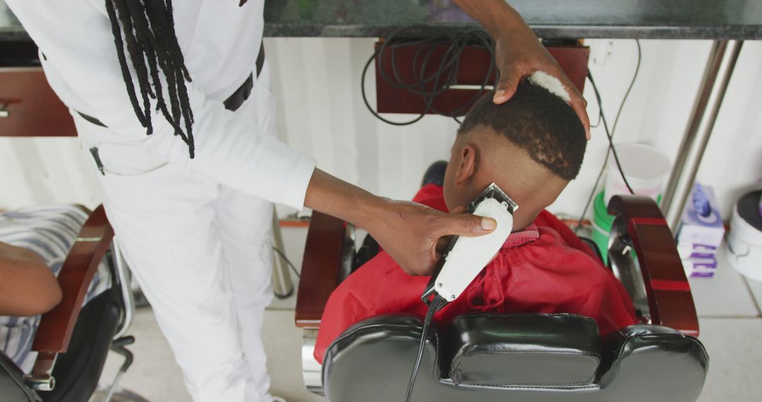 Barber Using Clippers to Trim Young Man's Hair in Barbershop - Free Images, Stock Photos and Pictures on Pikwizard.com