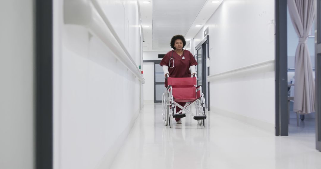 Nurse pushing empty wheelchair through hospital corridor in scrubs - Free Images, Stock Photos and Pictures on Pikwizard.com