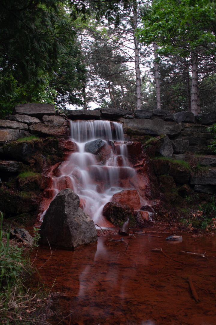 Tranquil Forest Waterfall with Red Soil and Boulders