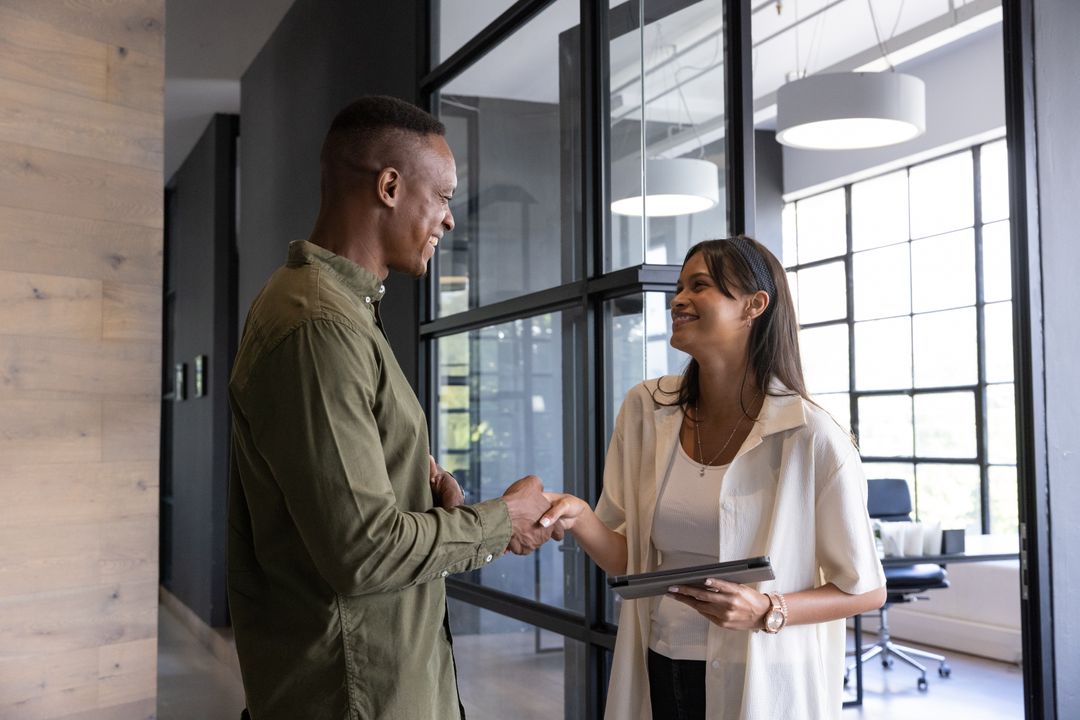 Smiling Colleagues Shaking Hands in Modern Office Environment