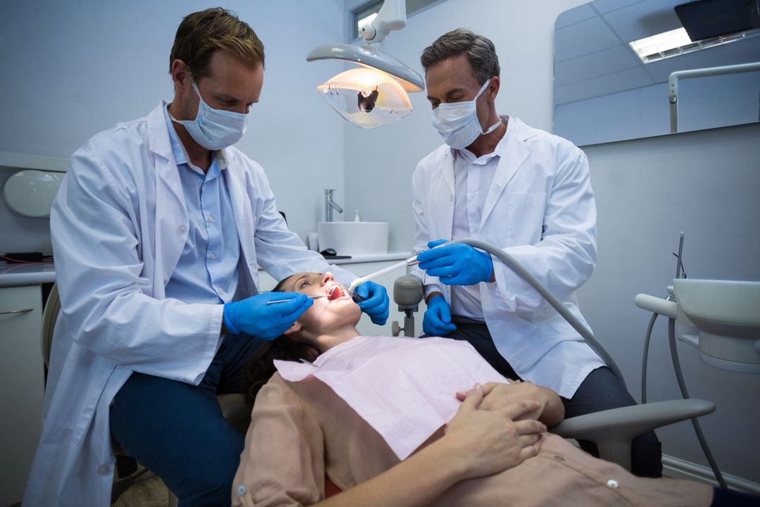 Dentists examining a female patient with tools - Free Images, Stock Photos and Pictures on Pikwizard.com