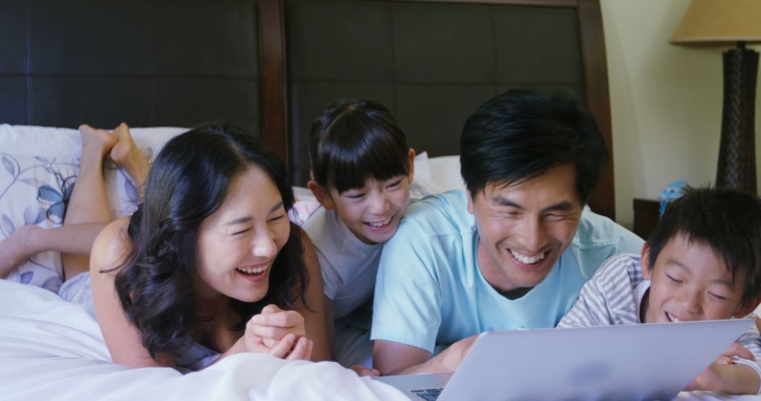 Happy Asian Family Laughing Together While Using Laptop