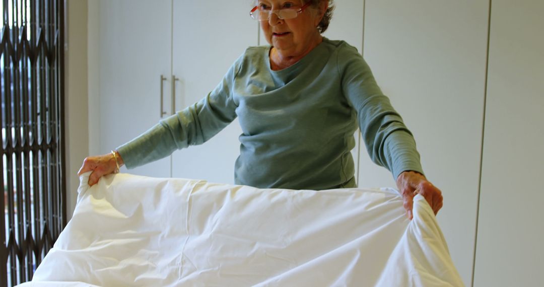 Senior Woman Folding Laundry in Modern Home Interior - Free Images, Stock Photos and Pictures on Pikwizard.com