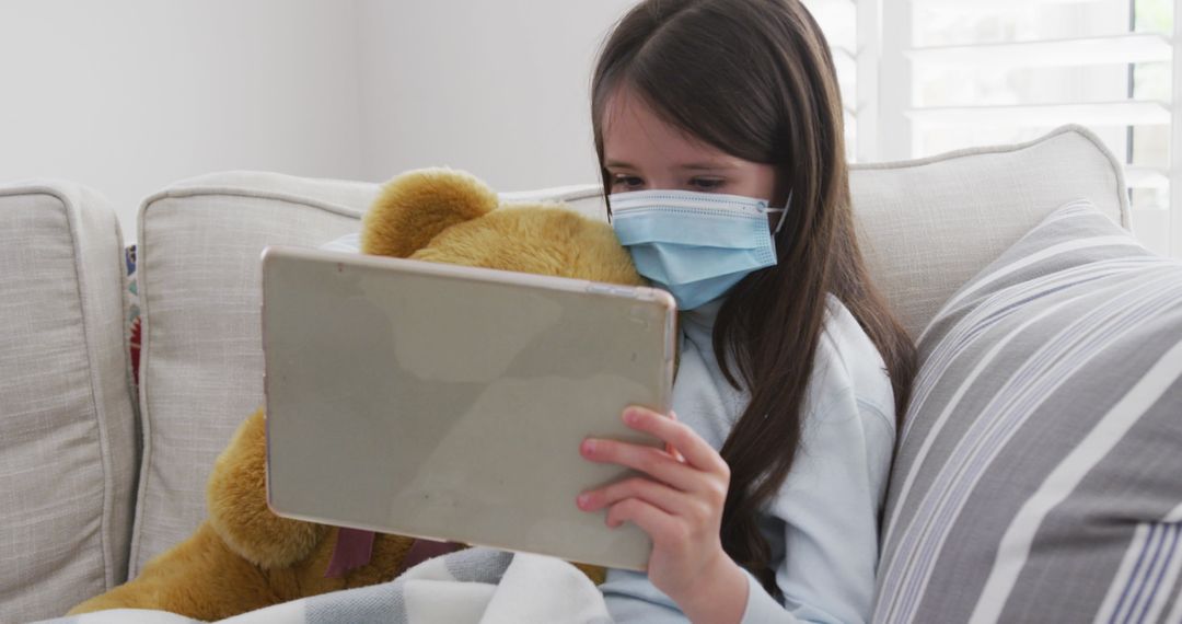 Young Girl with Teddy Bear Using Tablet in Pandemic Setting