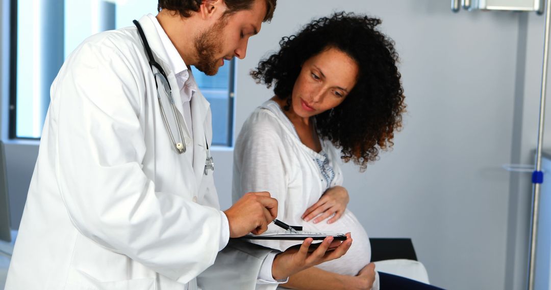 A doctor consults with a pregnant woman about prenatal health in a medical office. - Free Images, Stock Photos and Pictures on Pikwizard.com