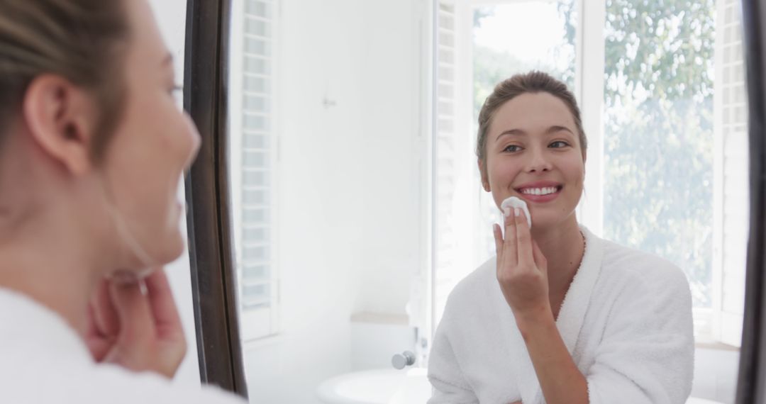 Smiling Woman Applying Skincare Product in Bathroom Mirror Reflection - Free Images, Stock Photos and Pictures on Pikwizard.com