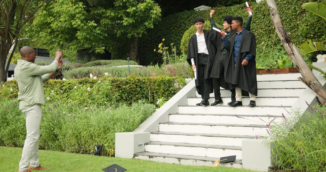 Dad Photographing Sons in Graduation Robes Celebrating on Steps