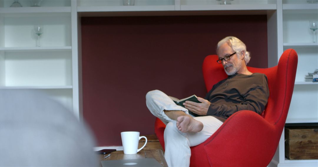 Senior Man Relaxing in Red Armchair Reading Book - Free Images, Stock Photos and Pictures on Pikwizard.com