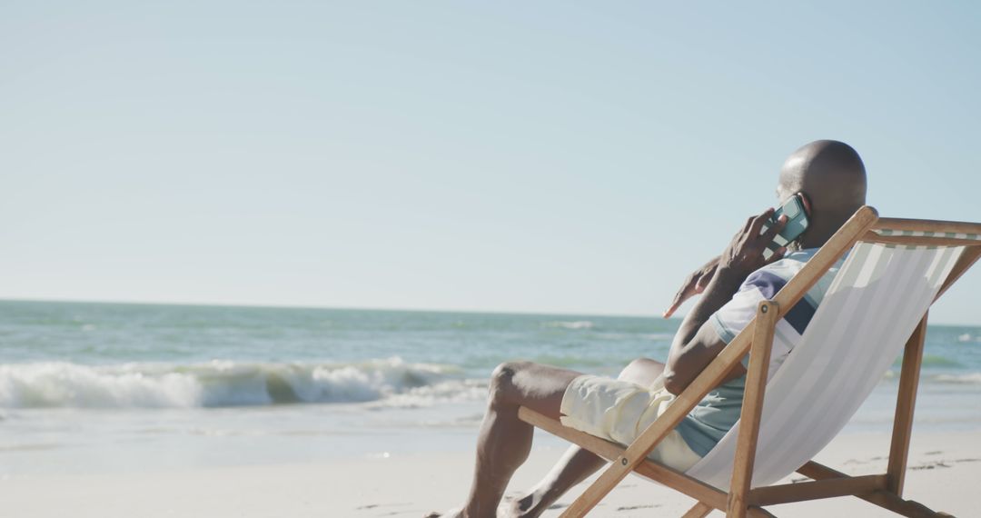 Man Relaxing on Beach Chair Making Phone Call by Ocean - Free Images, Stock Photos and Pictures on Pikwizard.com