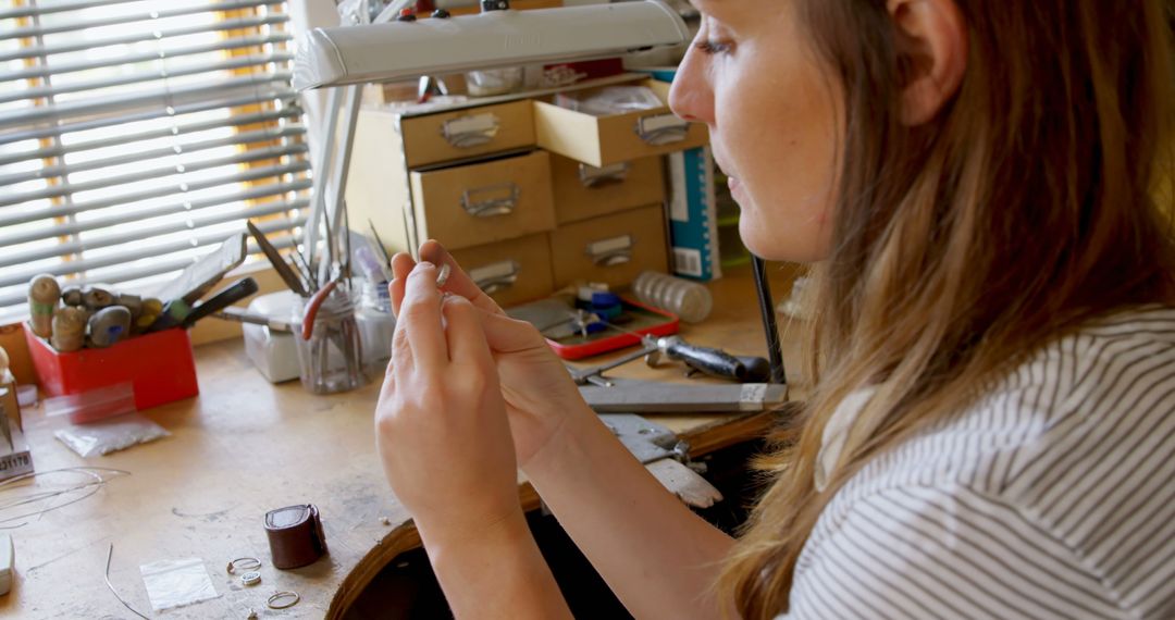 Young Woman Crafting Jewelry at Cluttered Workbench - Free Images, Stock Photos and Pictures on Pikwizard.com