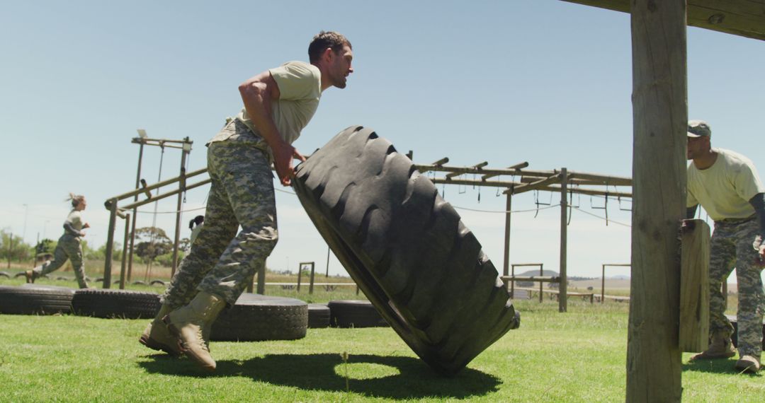 A fit soldier in fatigues trains by flipping a tyre in sunny boot camp conditions. - Free Images, Stock Photos and Pictures on Pikwizard.com