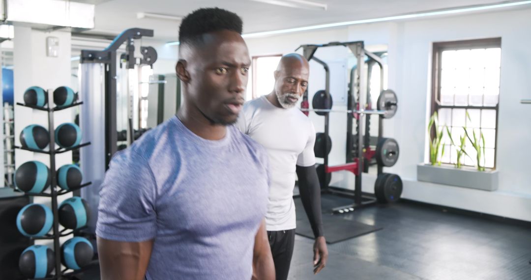 Trainer Guiding Gym Client at Squat Rack
