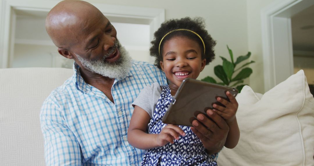 Happy Grandfather and Granddaughter Using Tablet Together