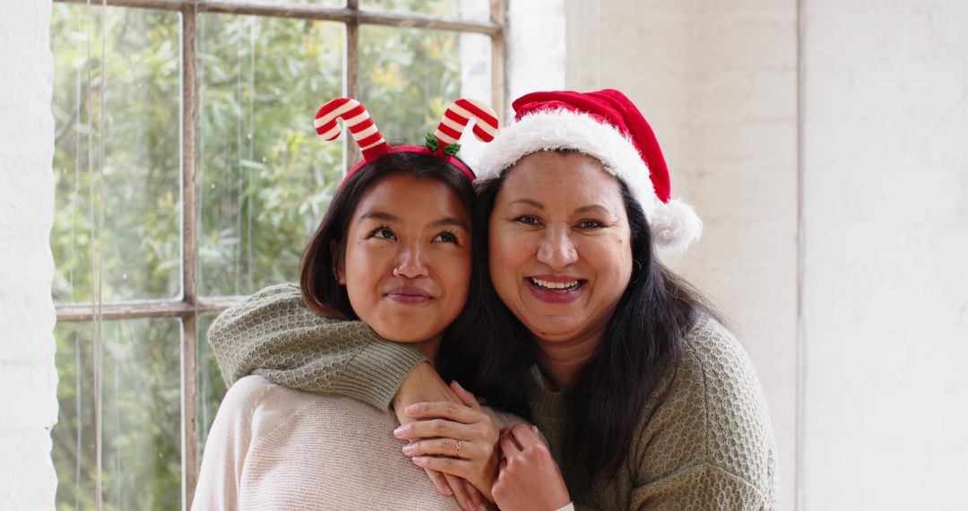 Smiling Mother and Daughter with Holiday Headwear by Window