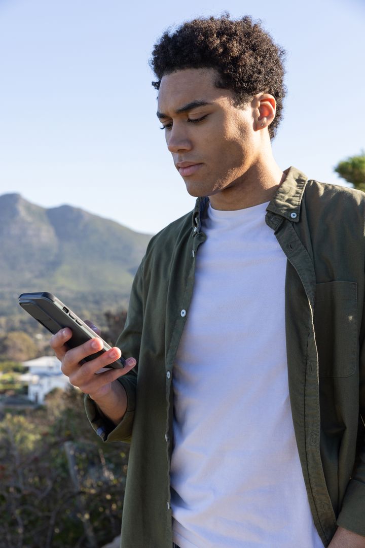 Casual Young Man Exploring Nature with Smartphone on a Sunny Day
