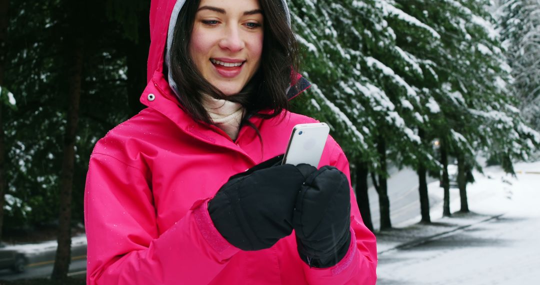 Woman Smiling While Using Smartphone in Winter Forest - Free Images, Stock Photos and Pictures on Pikwizard.com