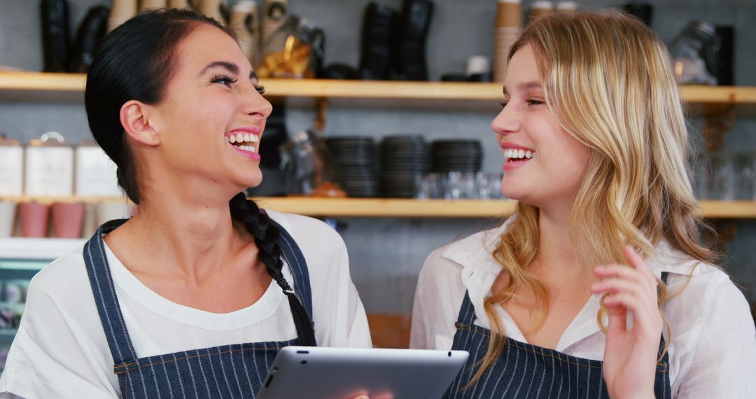 Two Baristas Laughing While Using Digital Tablet in Café - Free Images, Stock Photos and Pictures on Pikwizard.com