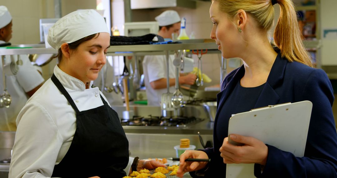 Chef presenting food samples to businesswoman in commercial kitchen - Free Images, Stock Photos and Pictures on Pikwizard.com