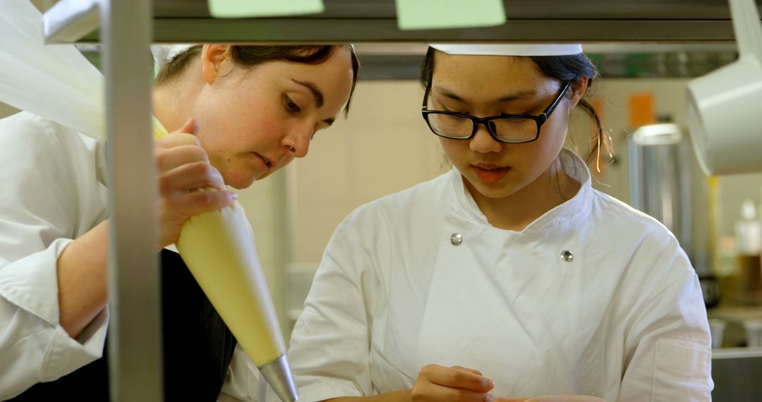 Pastry Chef Teaching Student Piping Techniques in Professional Kitchen - Free Images, Stock Photos and Pictures on Pikwizard.com