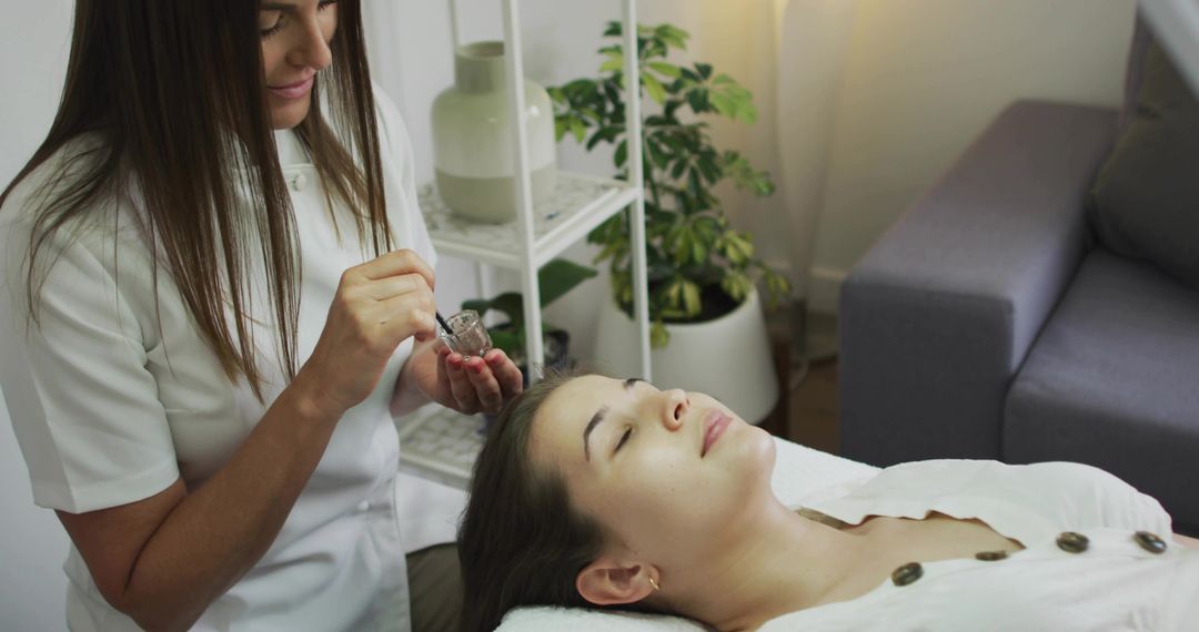 Esthetician applying eyebrow tint while client relaxing during spa beauty treatment